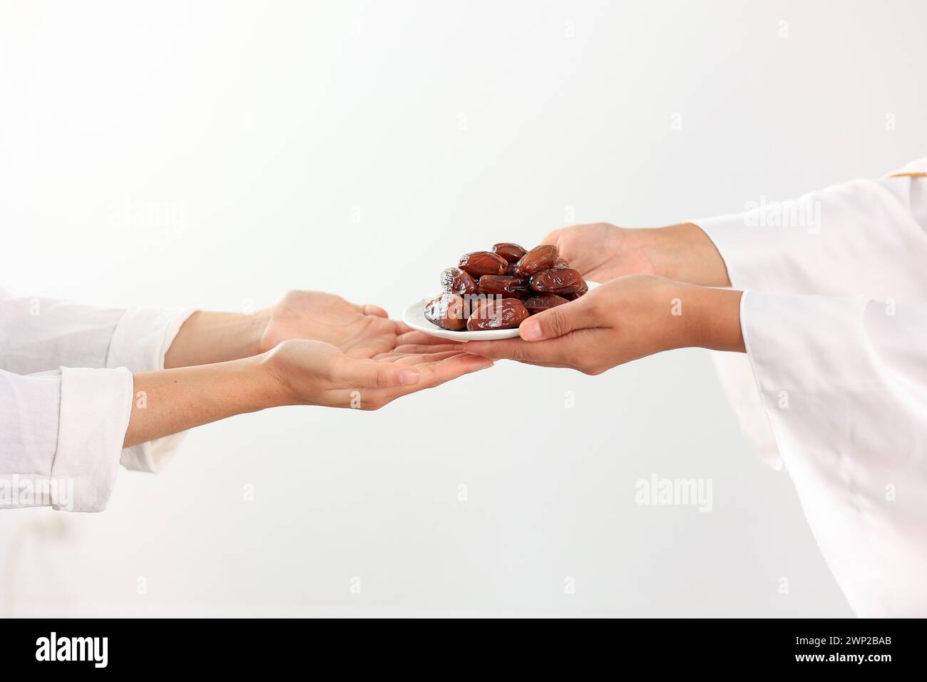 Concept Giving oder Charity während des Heiligen Monats Ramadhan überreichen muslimische Frauen Eine Platte mit Datteln Frucht Kurma an andere. Ifthar und Ramadan Kareem Comcept Stockfoto