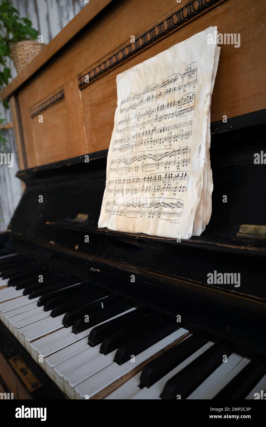 Schwarzes altes Klavier in Rissen mit Noten. Stockfoto