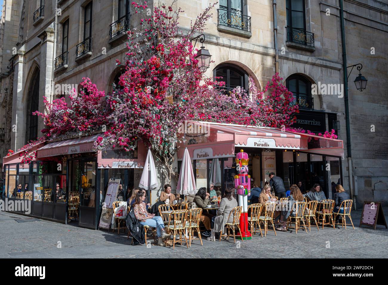 Fassade eines Pariser Cafés, bedeckt mit einer wunderschönen üppigen Blumendekoration. Künstliche Blumen sind ein neuer Trend bei der Dekoration von Cafés und Restaurants Stockfoto