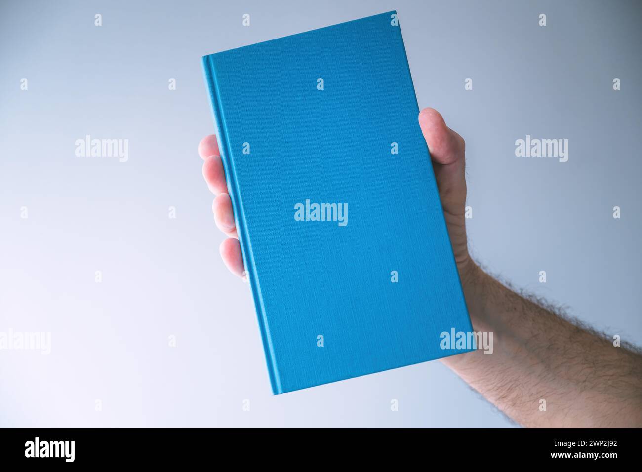 Blaues Hardcover Buch Mockup, Mann hält Buch, selektiver Fokus Stockfoto