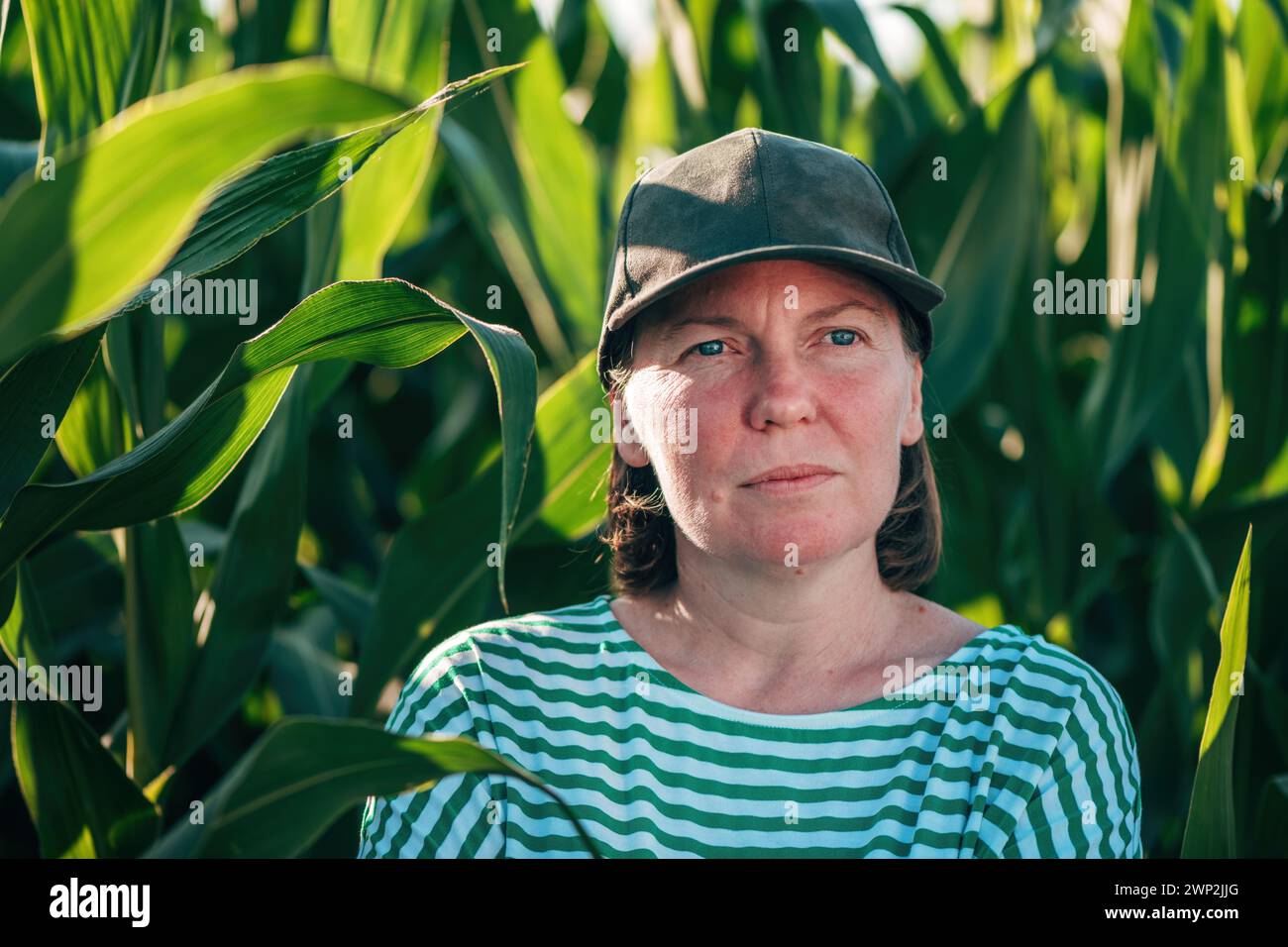 Landwirtin und Agrarwissenschaftlerin, die sich auf dem grünen Maisfeld ausgibt und in die Ferne blickt, während sie über einen selektiven Fokus nachdenkt Stockfoto