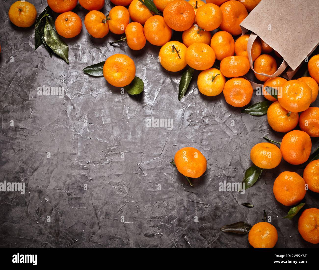 Flacher Bastelbeutel mit Mandarinen auf dem grauen Betonhintergrund, Vignette und Kopierraum. Raues Licht und Schatten. Stockfoto