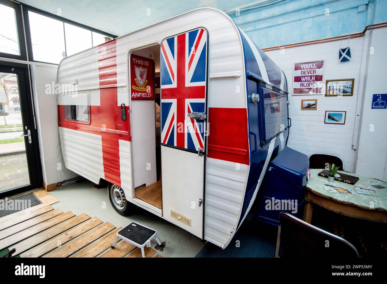 Bremen, Deutschland. Februar 2024. Ein Caravan, das in Großbritannien als Reiseziel gilt, findet man im HafenTraum-Indoor-Hostel-Camp. In einem ehemaligen Lagerhaus in Überseestadt können Gäste in Wohnwagen und Holzhütten übernachten, die nach Reisezielen gestaltet sind. Quelle: Hauke-Christian Dittrich/dpa/Alamy Live News Stockfoto