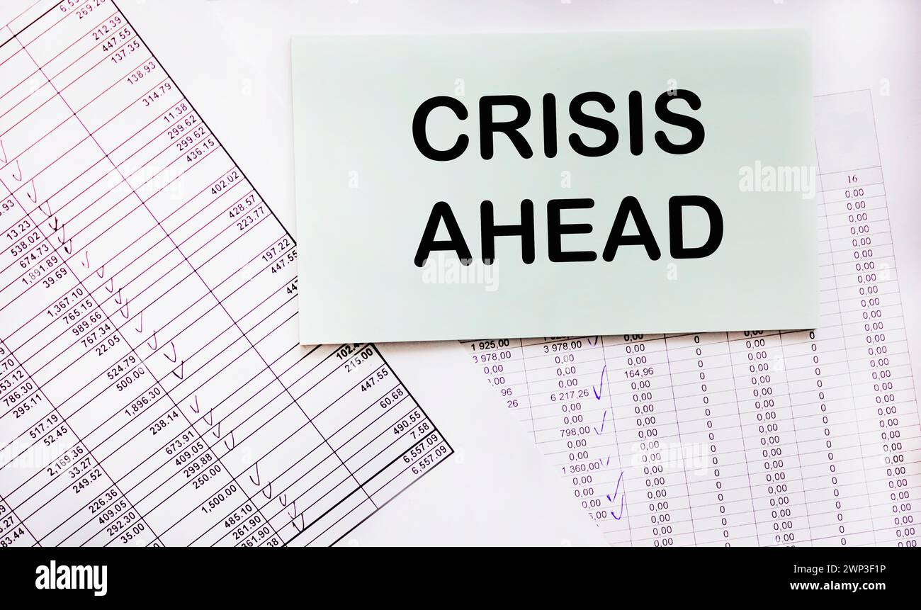 Notizblock mit dem Text vor dem Hintergrund finanzieller Berechnungen steht Eine Krise bevor. Wirtschaftskrise, Geschäftsversagen, Konkurskonzept. Schlecht neu Stockfoto