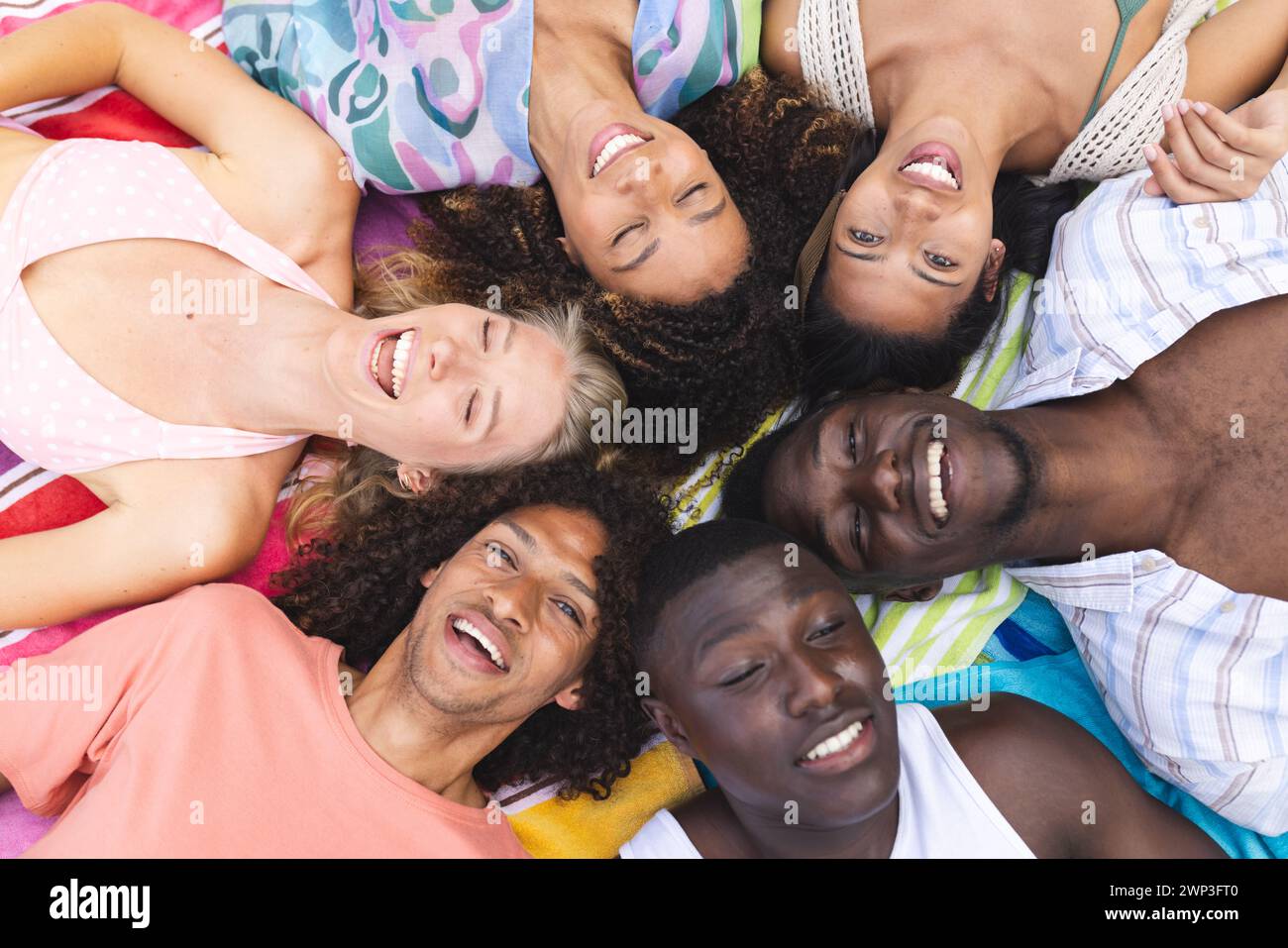 Verschiedene Gruppe junger Erwachsener, die im Kreis liegen und nach oben lächeln Stockfoto