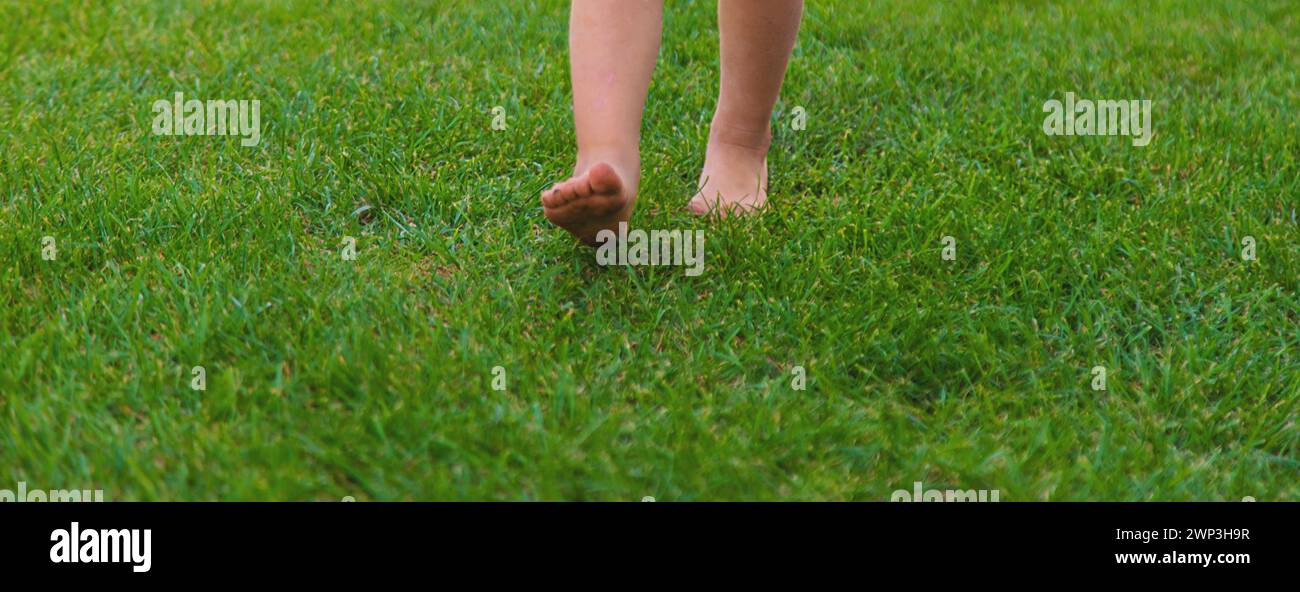 Kinderfüße auf dem Gras. Selektiver Fokus. Kind. Stockfoto