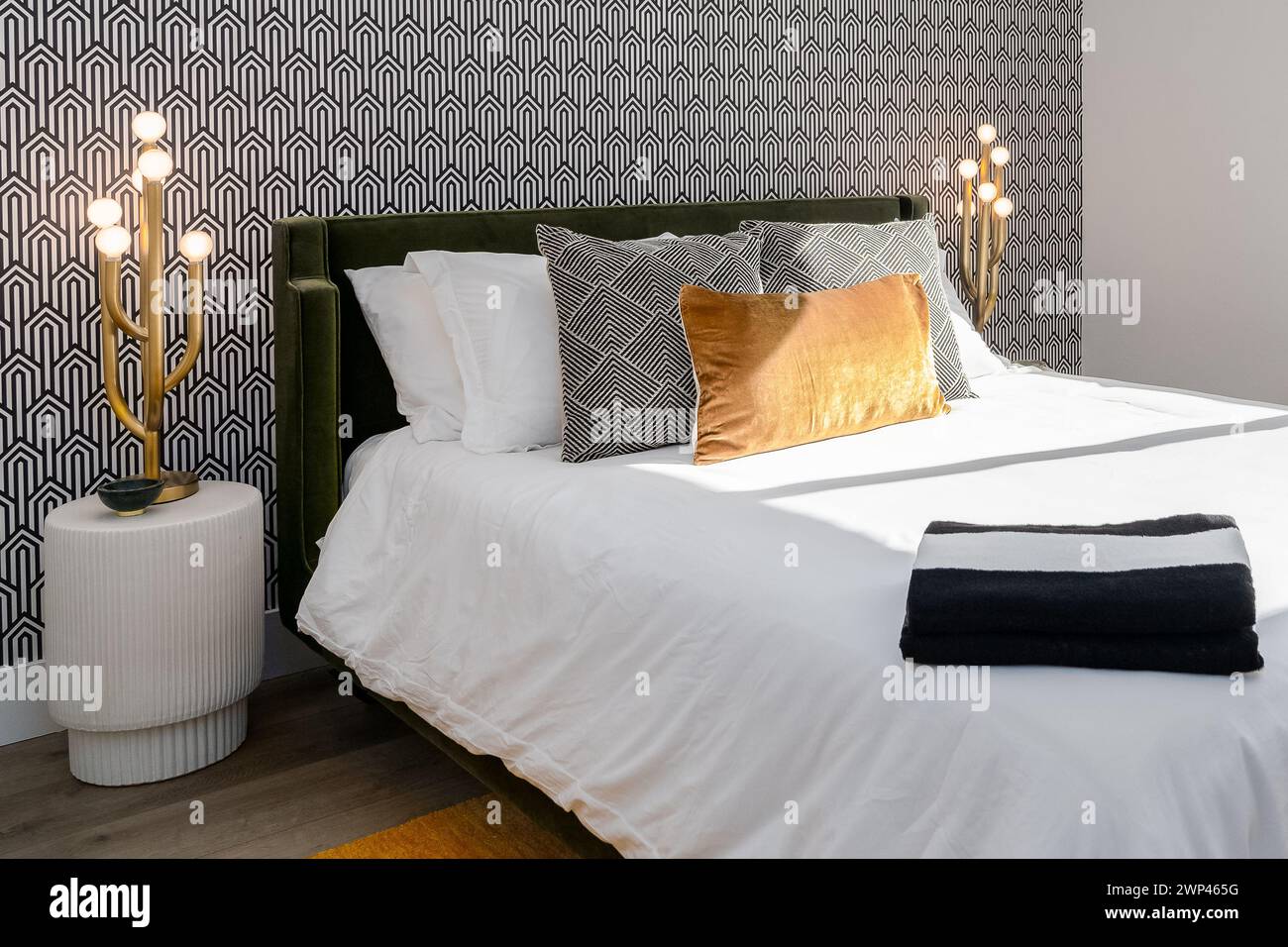 Luxuriöses schwarz-weißes Schlafzimmer mit goldenen Lampen, goldenen Kissen und kühler Tapete Stockfoto