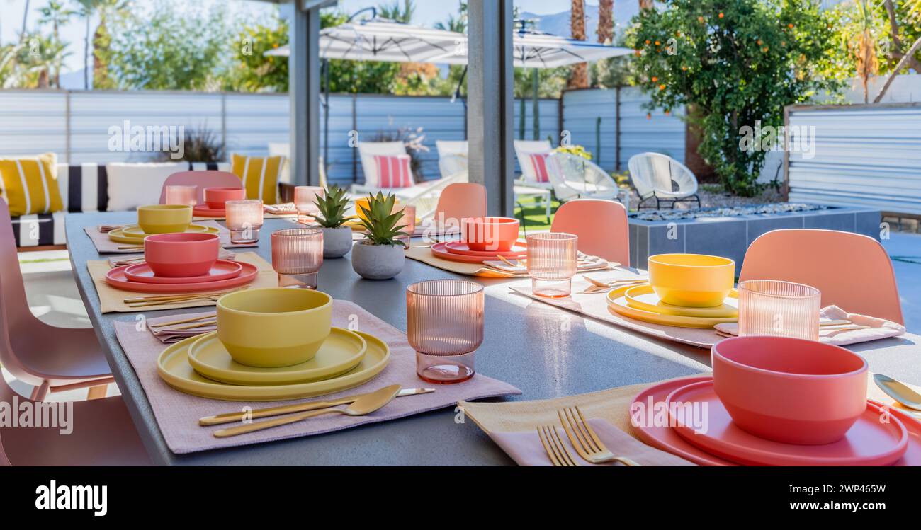 Terrasse im Hinterhof und Esstisch mit Schüsseln, Tellern, Gläsern und Besteck im Freien Stockfoto