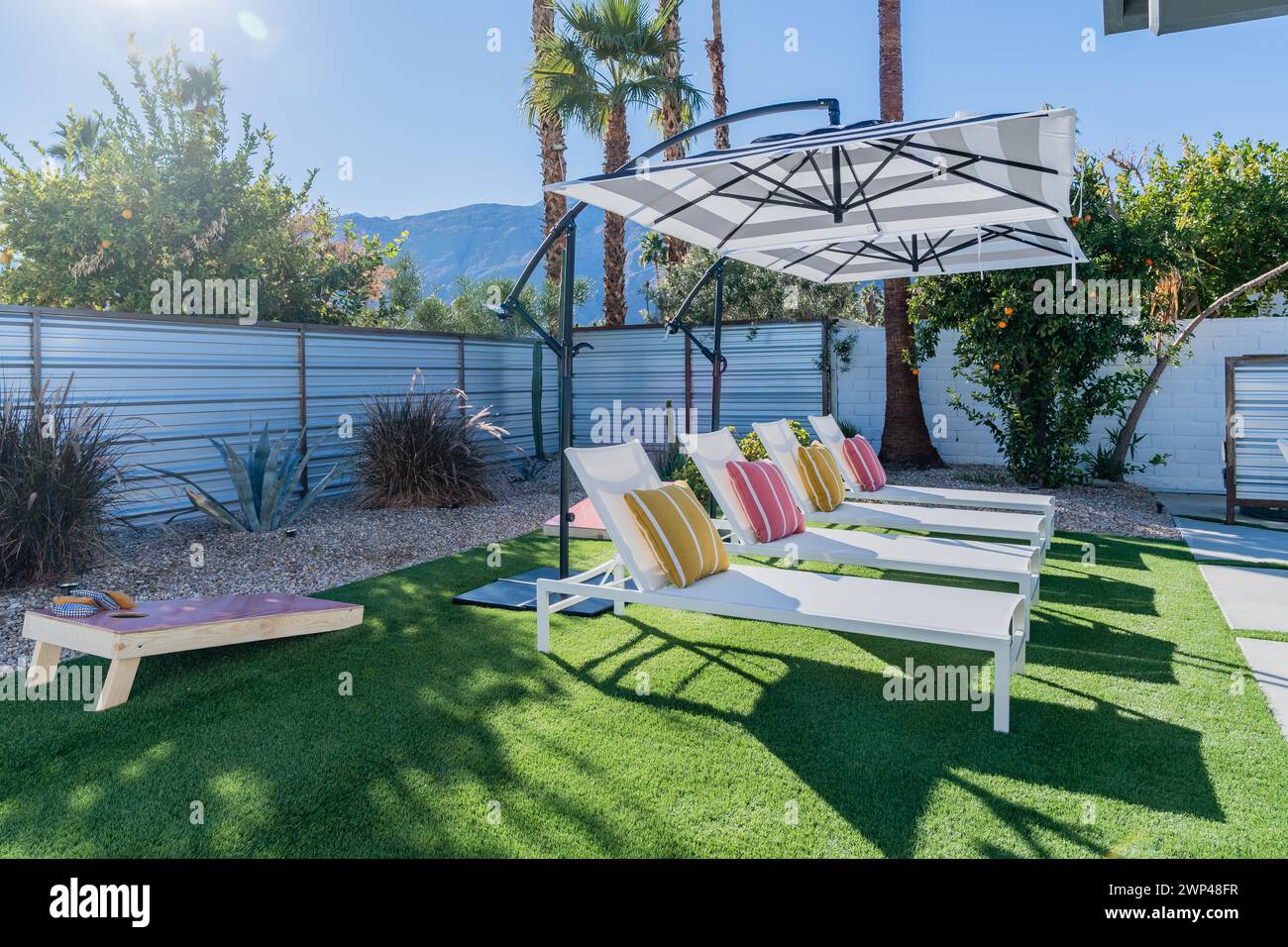 Liegestühle im Hinterhof mit Sonnenschirmen und Sonnenschein in Palm Springs, Kalifornien Stockfoto