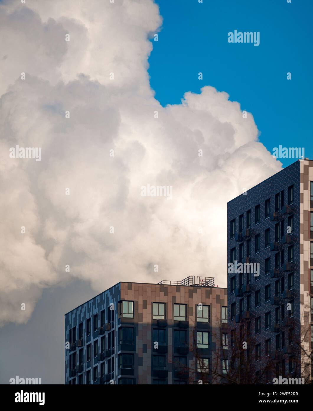 Die Fassade eines Wohngebäudes, ein Gebäude vor einem Hintergrund des blauen Himmels mit Wolken, moderne Immobilien Stockfoto