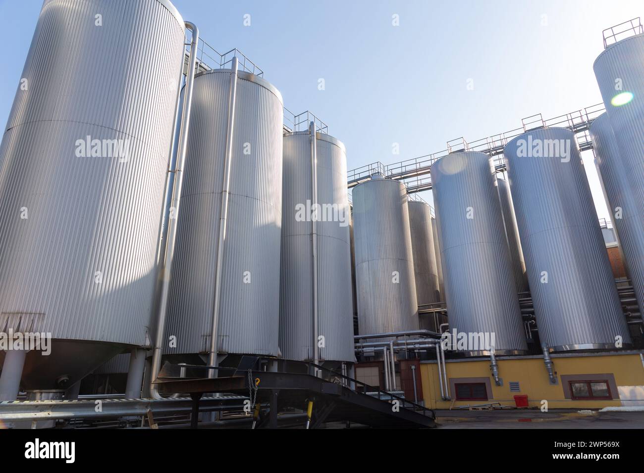 Brauereisilos oder -Tanks werden üblicherweise zur Lagerung von Gerste oder fermentiertem Bier verwendet. Brauereiausrüstung im Freien mit Edelstahltanks und -Rohren. Stockfoto