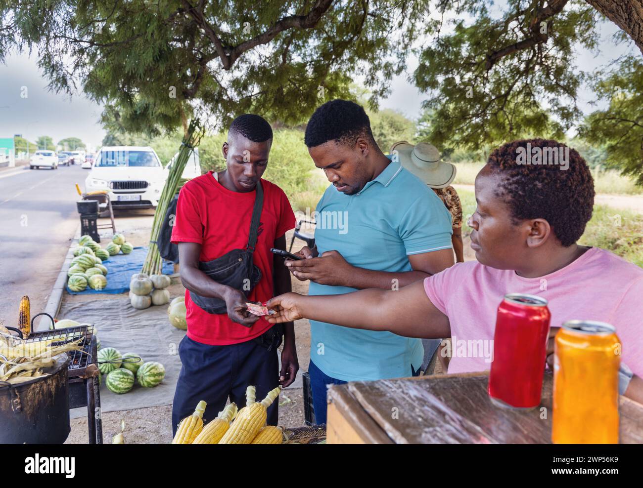 afrikanischer Straßenverkäufer, der Mais und Wassermelonen am Straßenrand verkauft Stockfoto