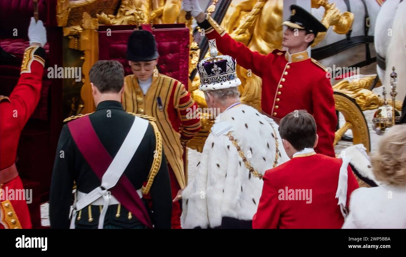 König Karl III. Krönung, verlässt Westminster Abbey an Bord des Gold State Coach, nach seiner Krönung am 6. Mai 2023. Er trägt die Krone des Staates (Imperial State Crown), uniformierte Wachen halten Regenschirme, um den König vor Regen zu schützen. Westminster Abbey Westminster London UK Stockfoto