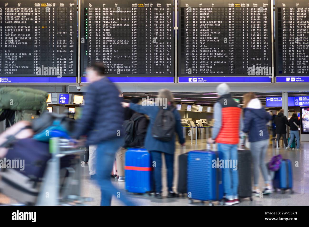 Flughafen Frankfurt, Deutschland - 19. Februar 2024: Menschen in Bewegung verschwimmen beim Stehen und Gehen vor einer Anzeigetafel für den Abflug Stockfoto