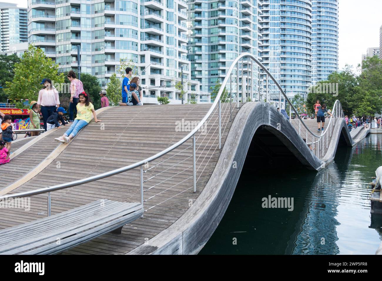 Touristen und Fußgänger versuchen, auf dem Simcoe Wave Deck zu laufen, einem fantasievollen Beispiel urbaner Kunst am Harbourfront in der Innenstadt von Toronto, Ontario. Stockfoto