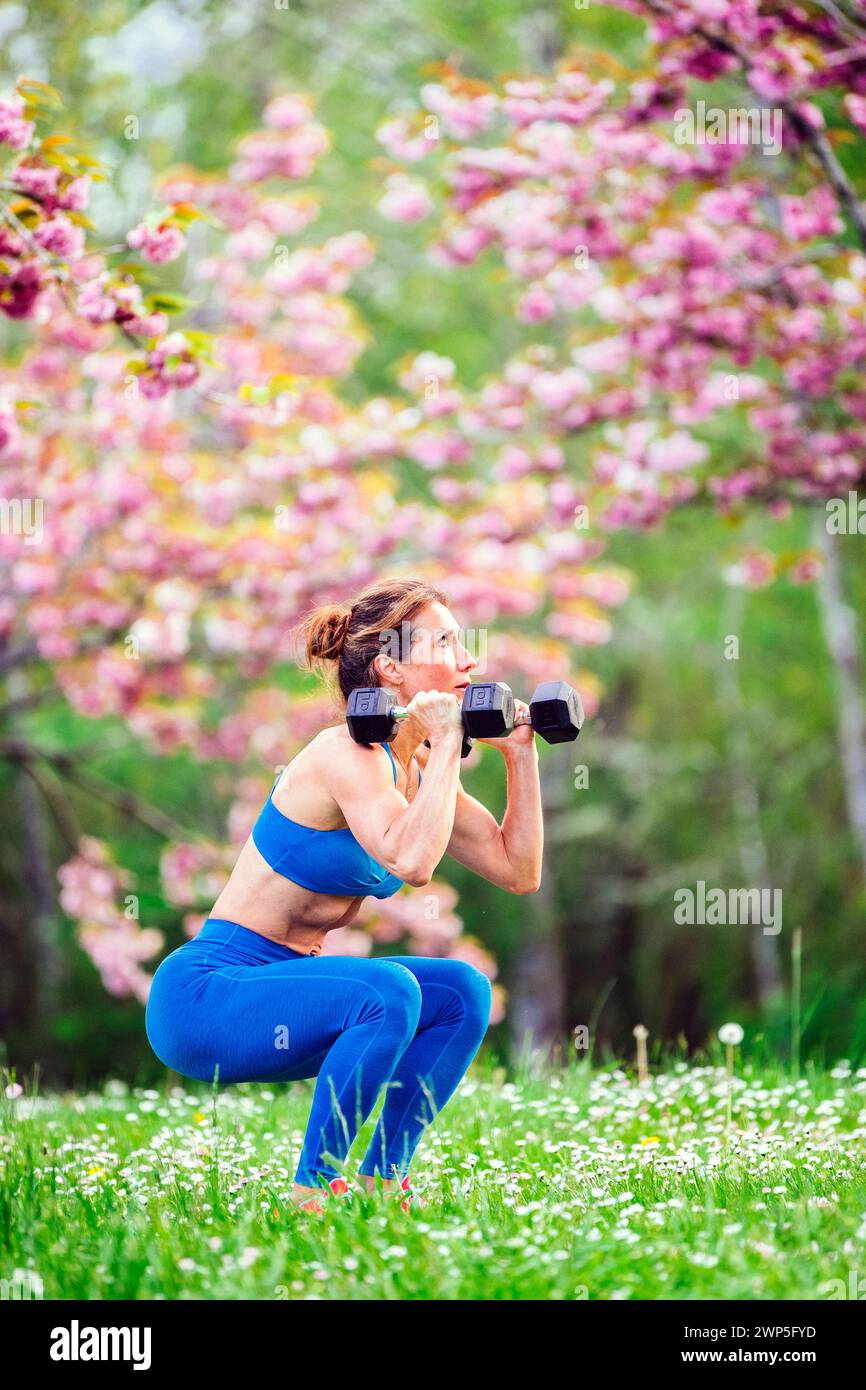 Weibliche Athletin trainiert in Sportbekleidung zwischen Kirschbäumen Stockfoto