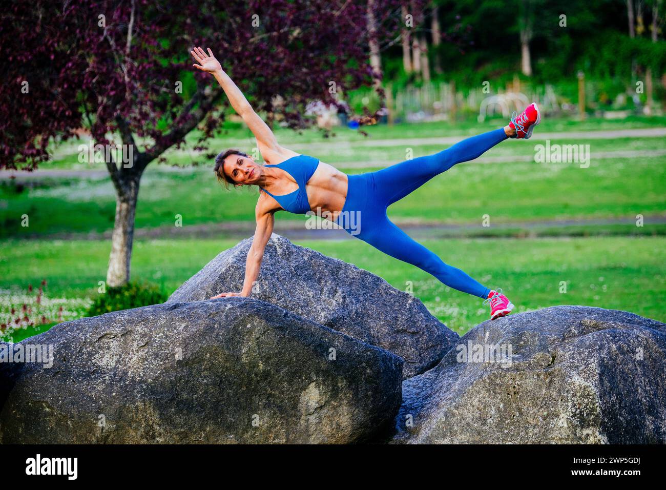 Weibliche Athletin trainiert in Sportbekleidung zwischen Kirschbäumen Stockfoto