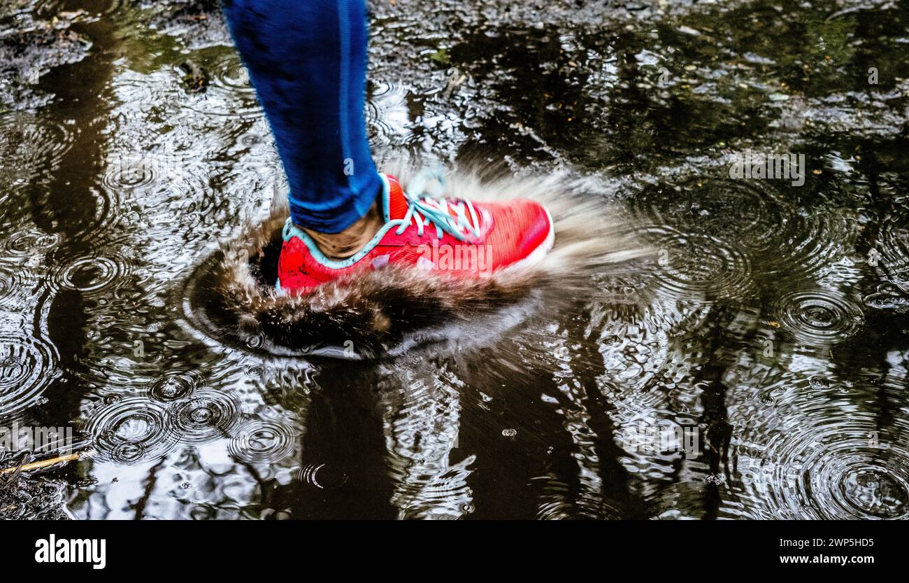 Weibliche Athletin, die durch die Pfütze läuft Stockfoto