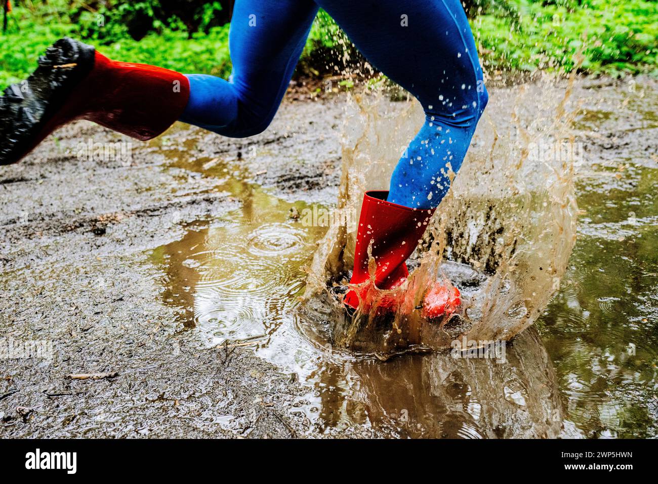 Weibliche Athletin, die durch die Pfütze läuft Stockfoto