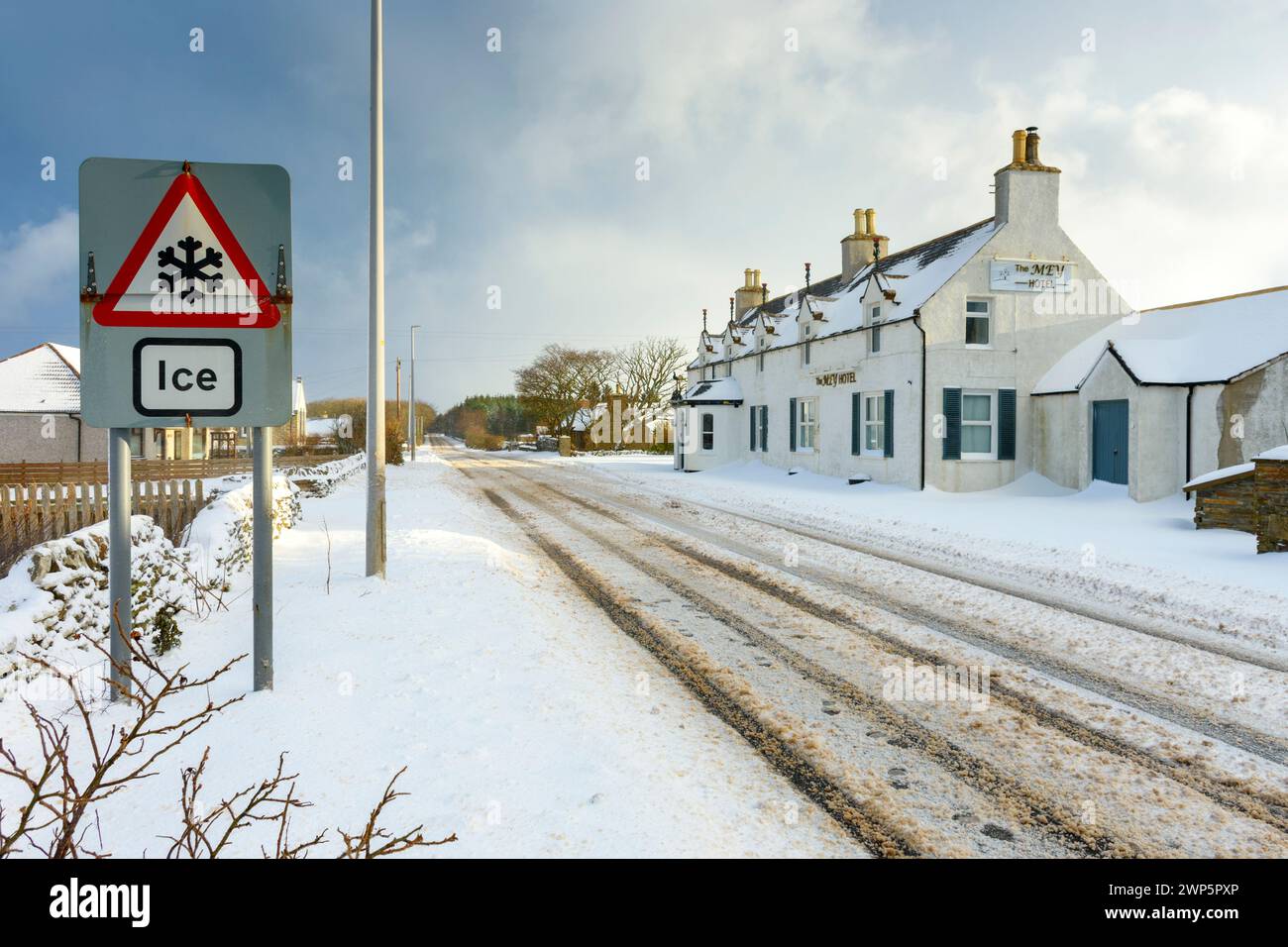 Das Mey Hotel und ein „Ice“-Warnschild an der A836-Hauptstraße bei schneebedecktem Wetter im Dorf Mey, Caithness, Schottland, Großbritannien Stockfoto