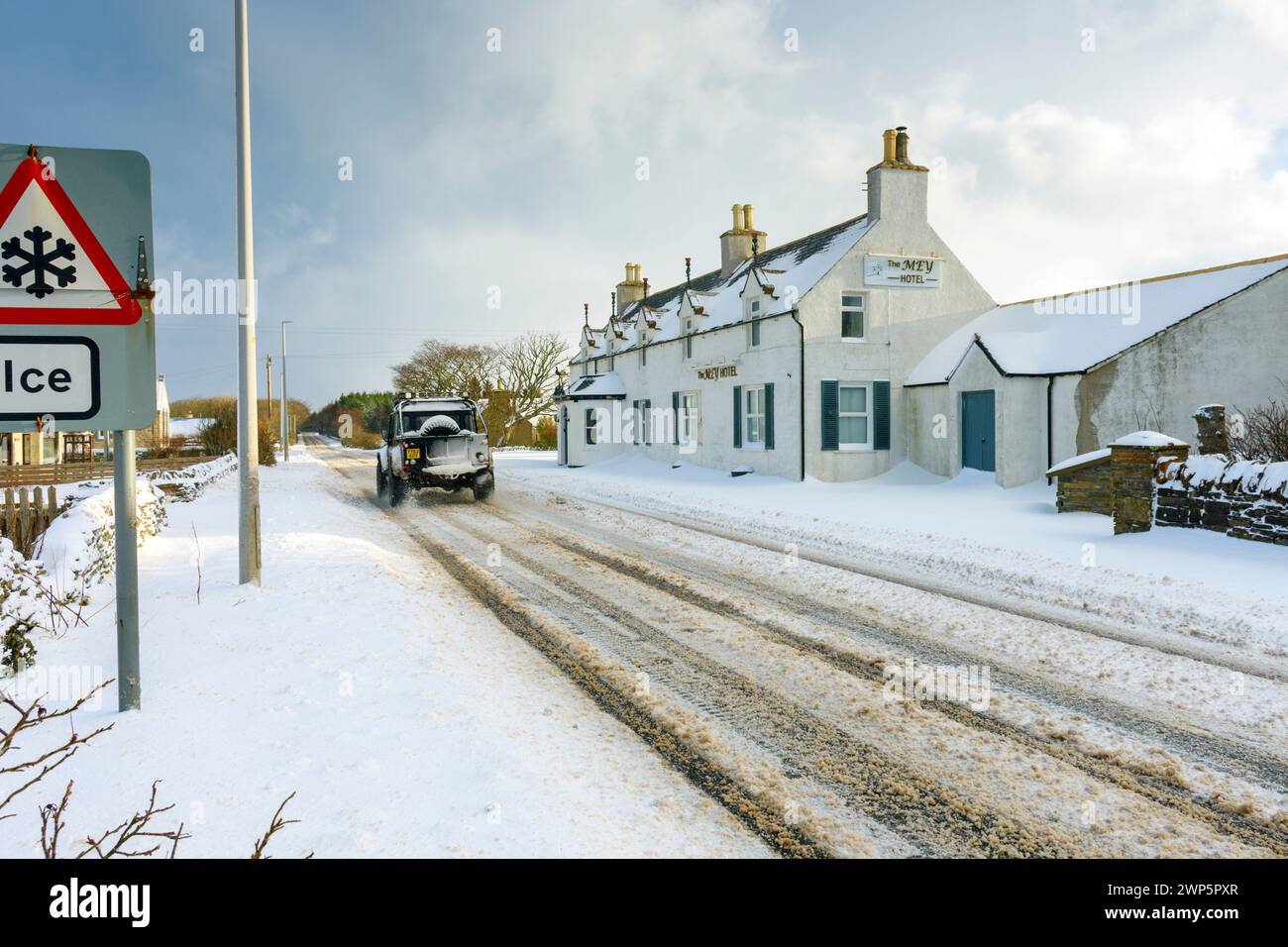 Das Mey Hotel und ein „Ice“-Warnschild an der A836-Hauptstraße bei schneebedecktem Wetter im Dorf Mey, Caithness, Schottland, Großbritannien Stockfoto