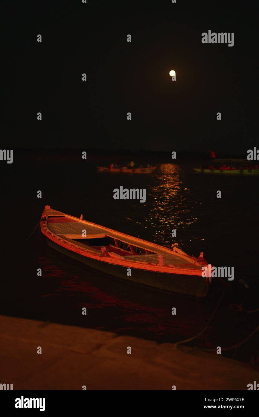 Holzboot am Flussufer von Ganga in Varanasi im Licht des Vollmondes gebunden (einen Tag vor Vasant poornima). Stockfoto