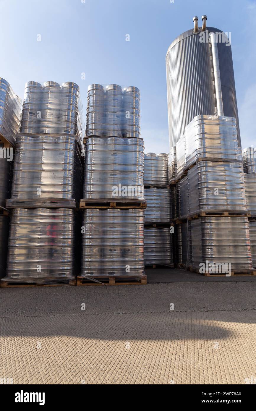 Große Menge an Aluminium-Bierfässern, die mit Euro-Paletten übereinander gestapelt und mit Vinylfolie umwickelt sind. Das Bier, das zum Versand bereit ist, ist eine Flasche Stockfoto