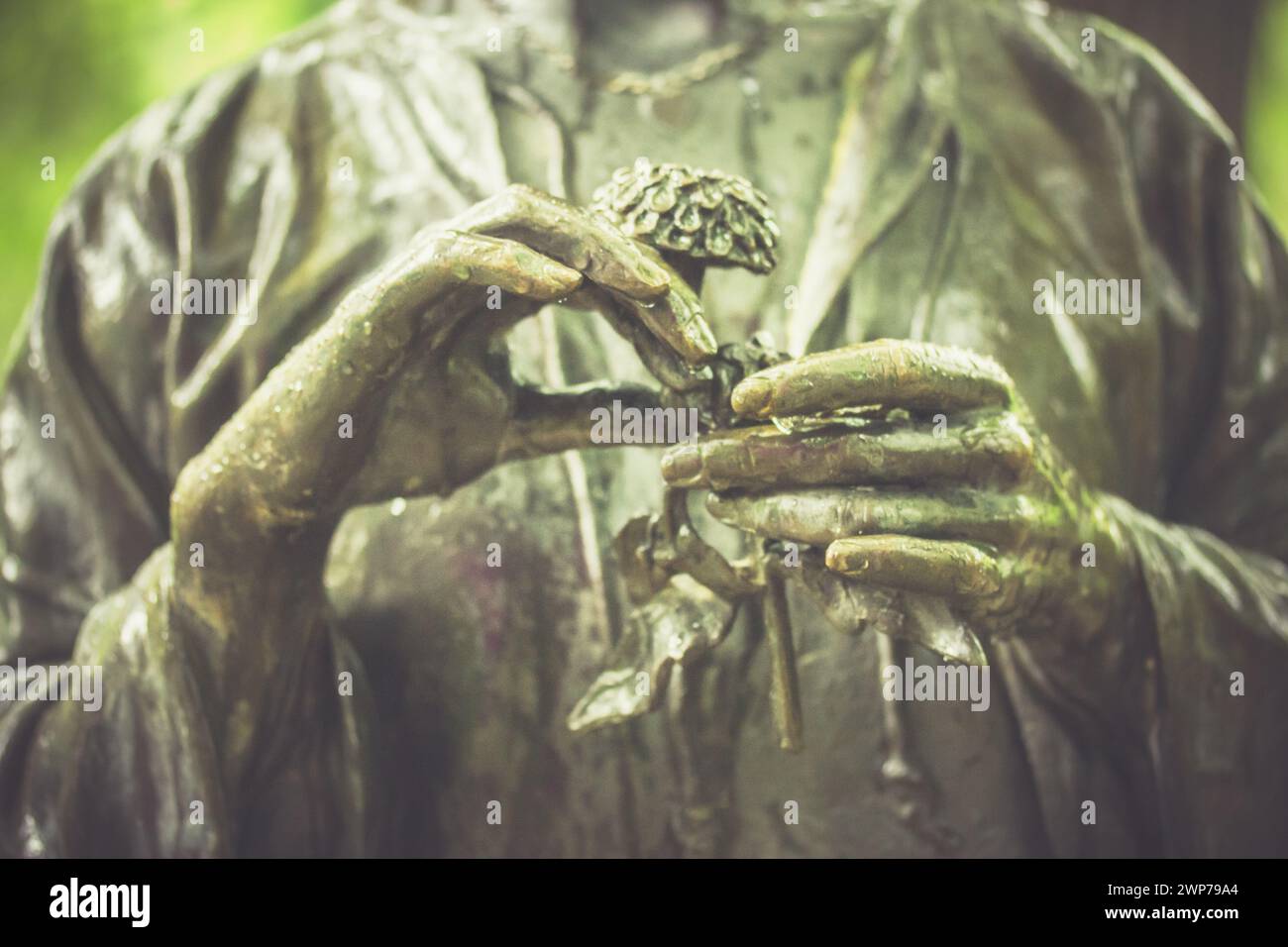 Skulptur mit Schwerpunkt auf Frauenhänden. Zarte Pflanze in der Hand der Frau. Romantisches nostalgisches Foto. Mysteriöses Frauenkmal. Blumenreichtum erzählen. Stockfoto