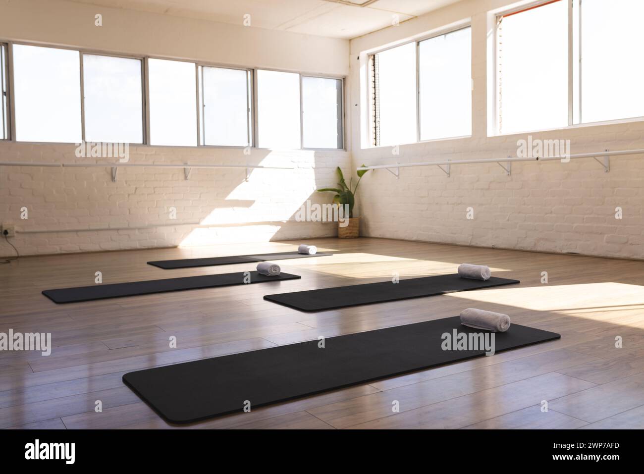 Ein ruhiges Yoga-Studio erwartet die Praktizierenden, in natürliches Licht getaucht, mit Kopierraum Stockfoto