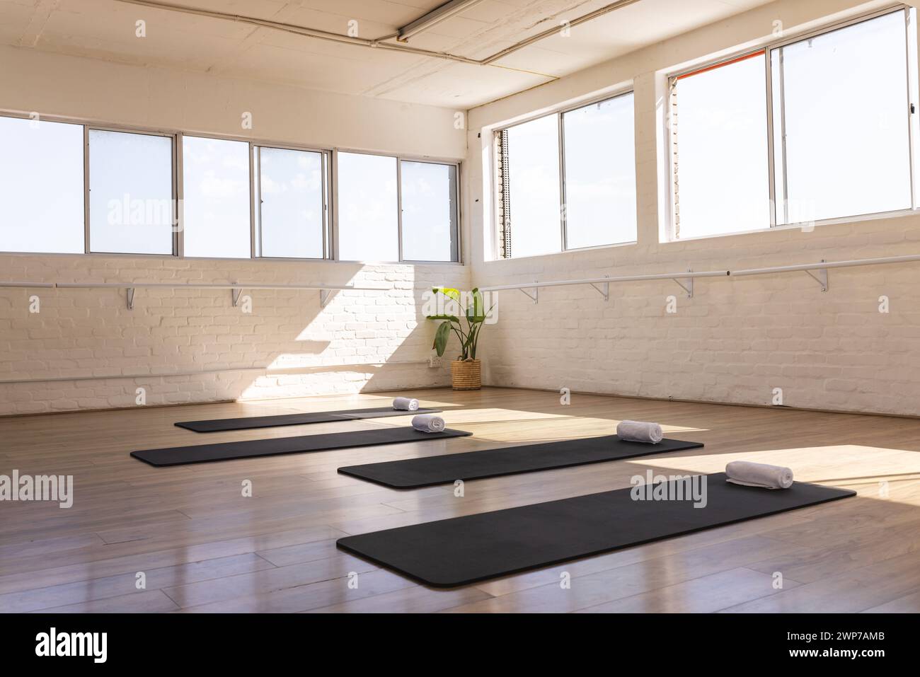 Ein ruhiges Yoga-Studio erwartet die Praktizierenden, in natürlichem Licht mit Kopierraum getaucht Stockfoto