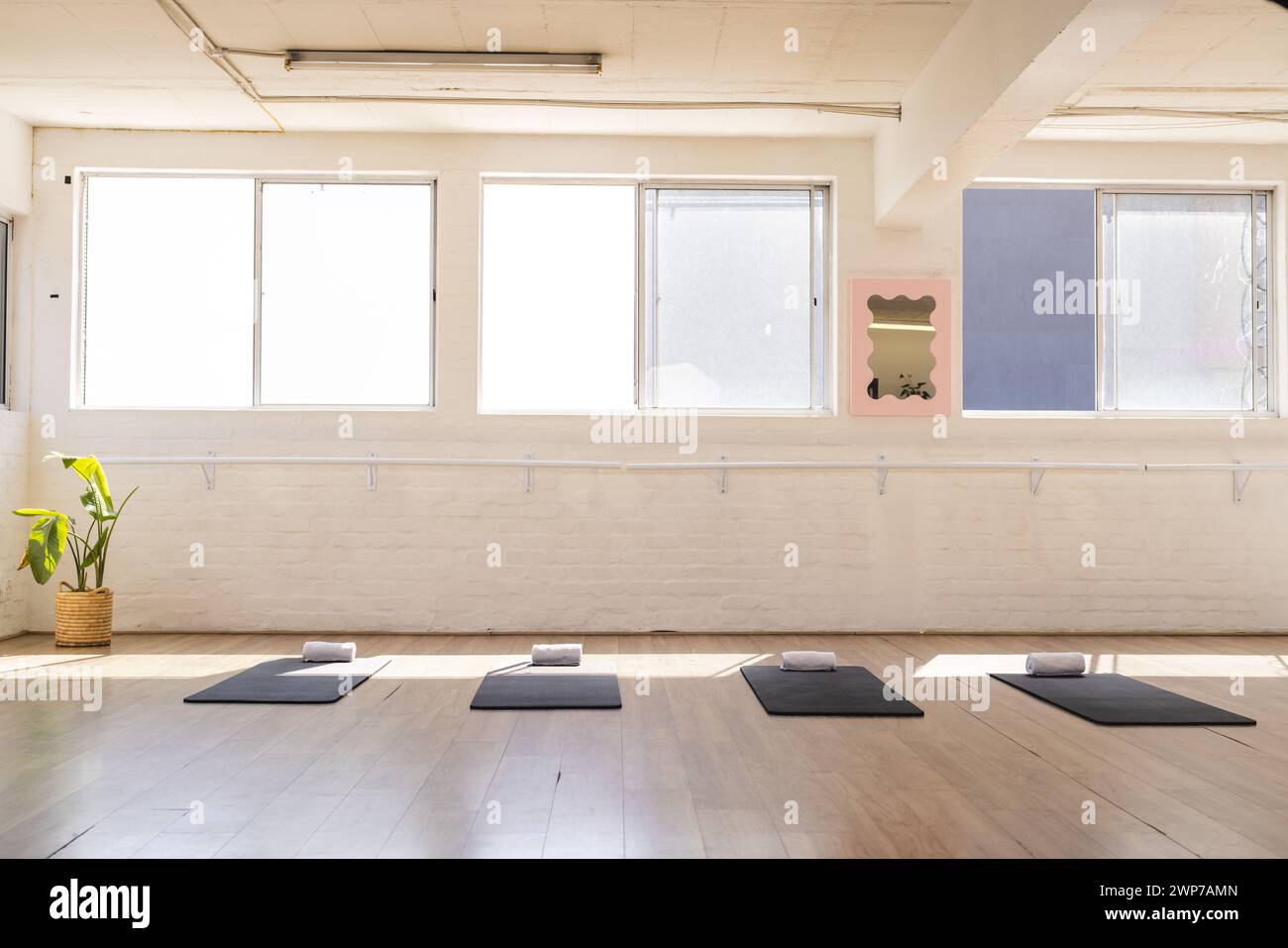 Sonnenlicht durchflutet ein ruhiges Yoga-Studio mit Kopierraum Stockfoto