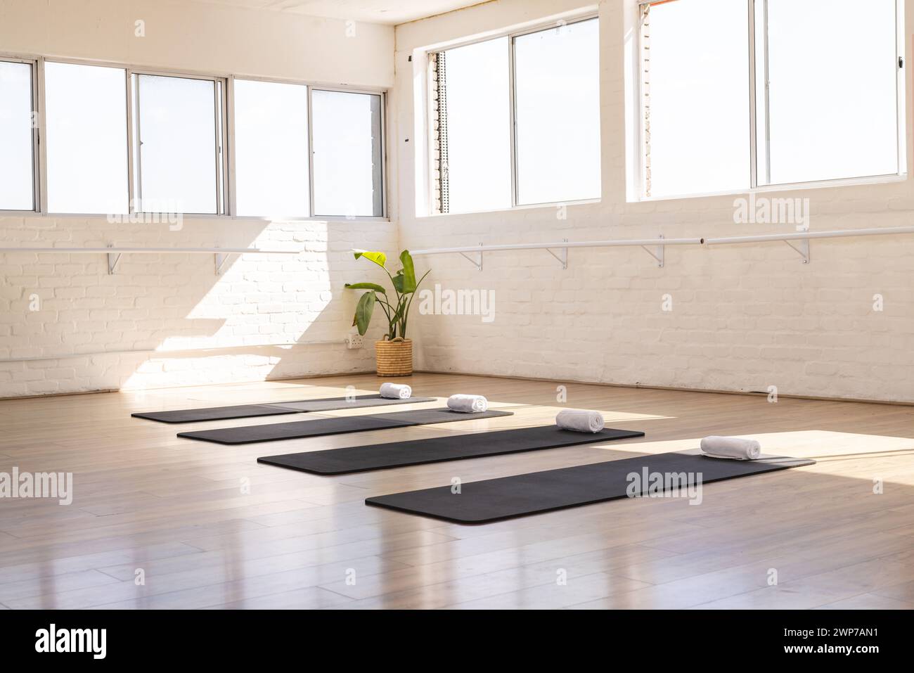 Ein ruhiges Yoga-Studio erwartet die Praktizierenden, in natürliches Licht getaucht, mit Kopierraum Stockfoto