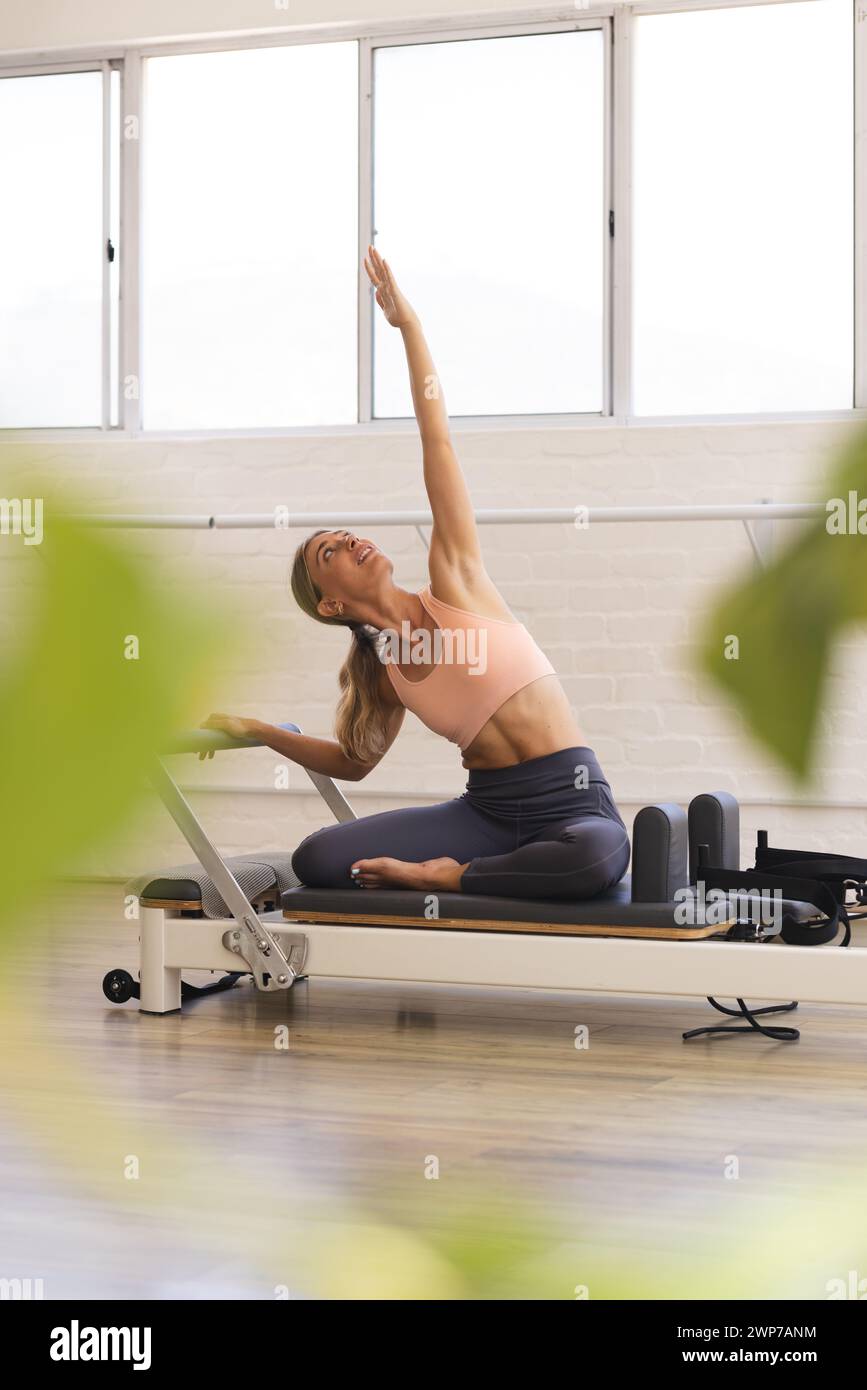 Die junge weiße Frau spielt einen Pilates-Reformator in einem Fitness-Studio Stockfoto