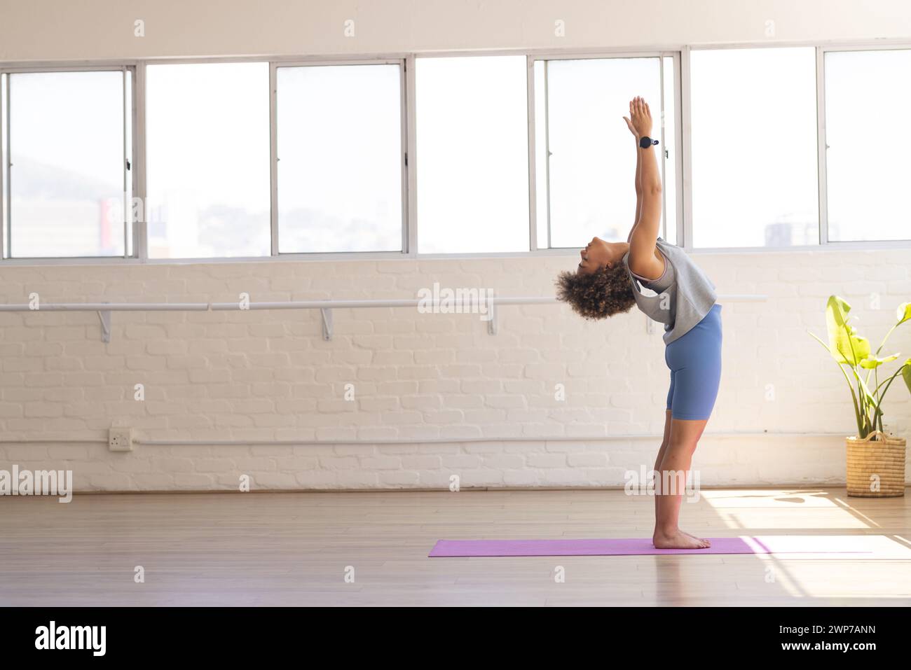 Junge birassische Frau übt Yoga in einem hellen Studio mit Kopierraum Stockfoto