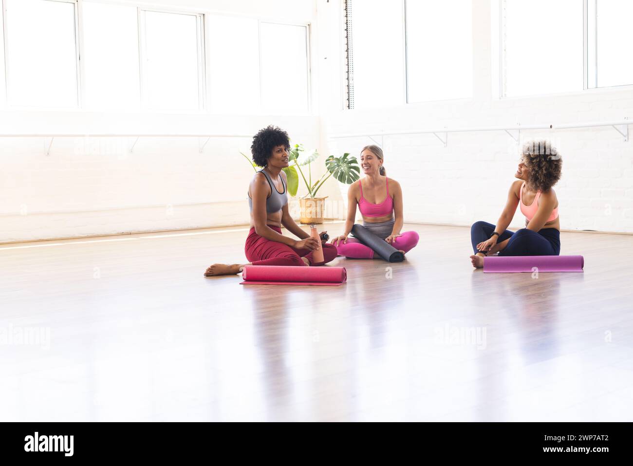 Drei Frauen entspannen sich nach einer Yoga-Session in einem hellen Studio mit Kopierraum Stockfoto