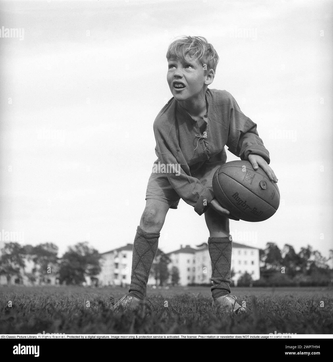 Rugby 1940. Ein junger Rugbyspieler hält den Rugbyball in den Händen. Der Rugbyball hat eine ovale Form, vier Panels und ein Gewicht von etwa 400 Gramm. 1942. Kristoffersson Ref. A57-1 Stockfoto