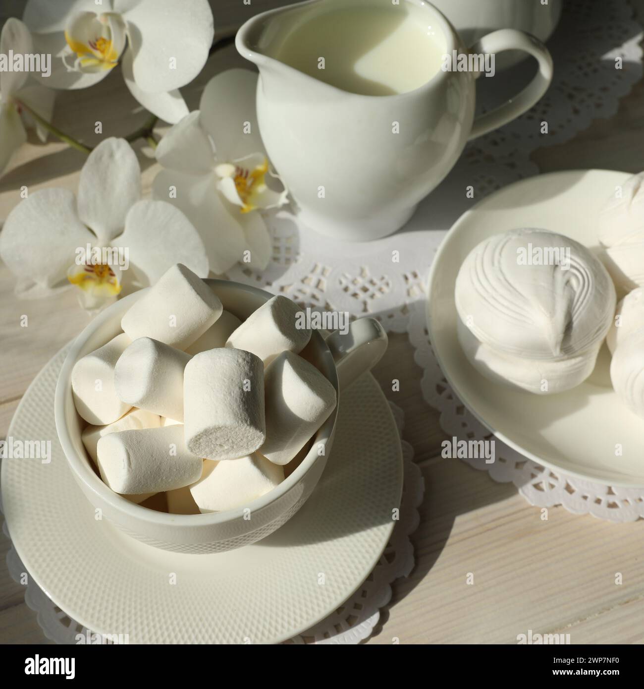 Frühjahrsfrühstück mit Marshmallow, Kaffee und Milch. Flatlay mit Nahrung und Blume in weißer Farbe Stockfoto