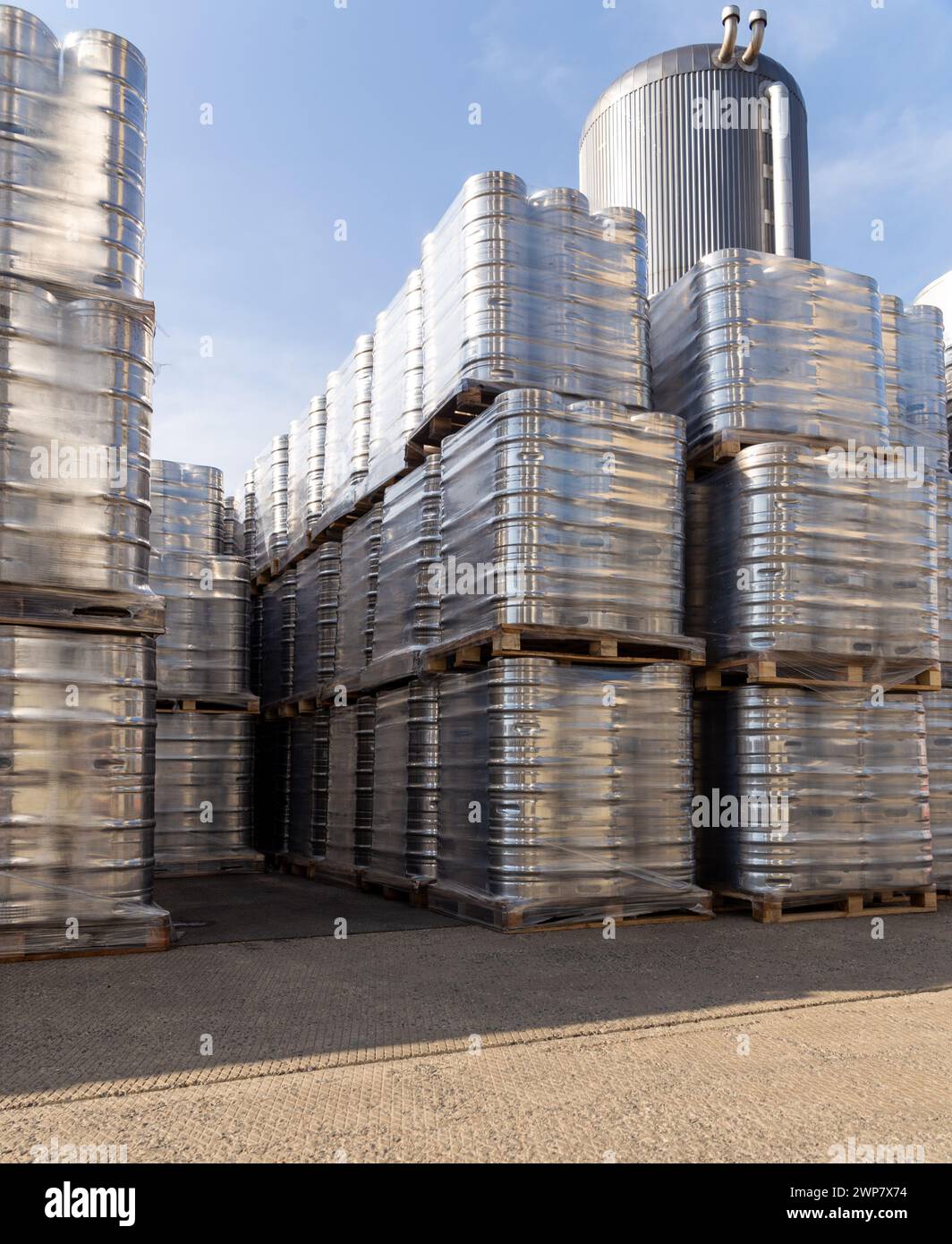 Große Menge an Aluminium-Bierfässern, die mit Euro-Paletten übereinander gestapelt und mit Vinylfolie umwickelt sind. Das Bier, das zum Versand bereit ist, ist eine Flasche Stockfoto