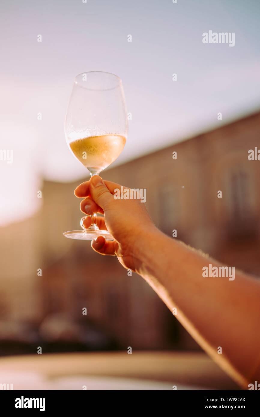 Hand des Mannes sitzt im Restaurant im Freien mit einem Glas Weißwein oben, Portugal Stockfoto