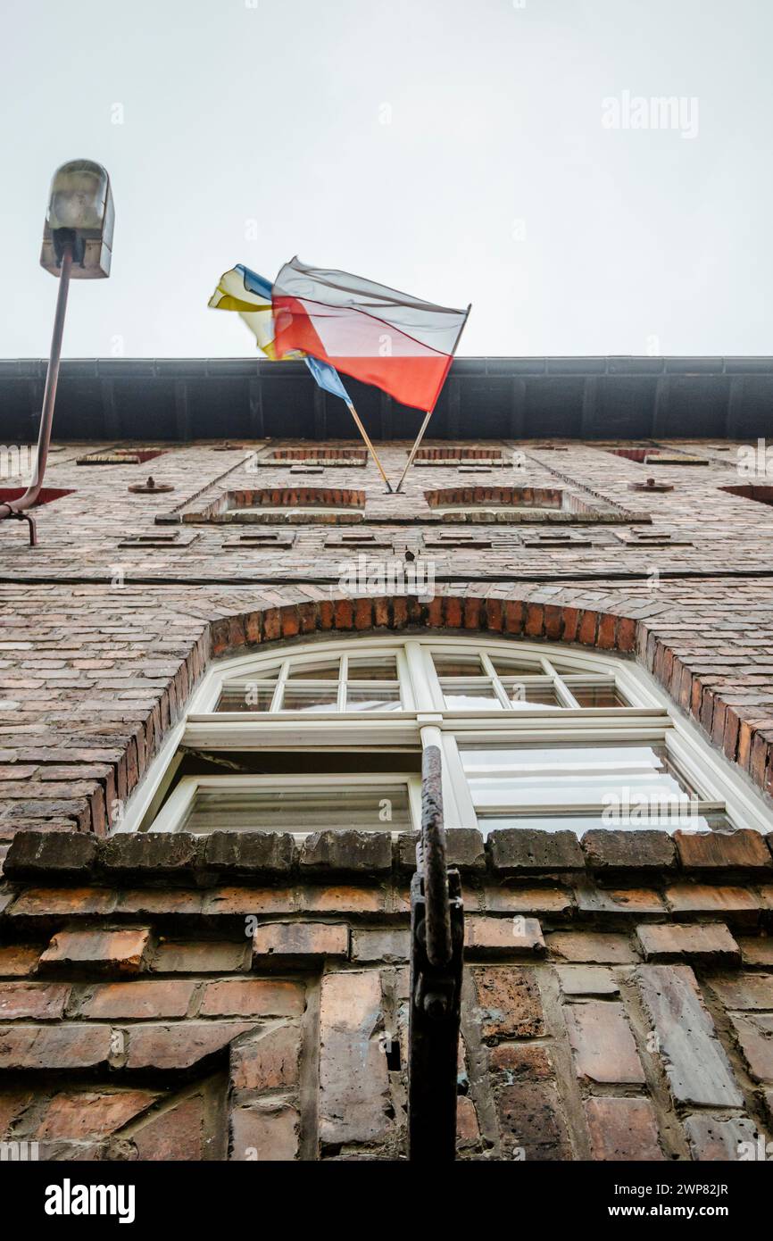 Polnische und ukrainische Flagge schwenken zusammen auf Ziegelhaus in Kattowitz Nikiszowiec, Südpolen Stockfoto