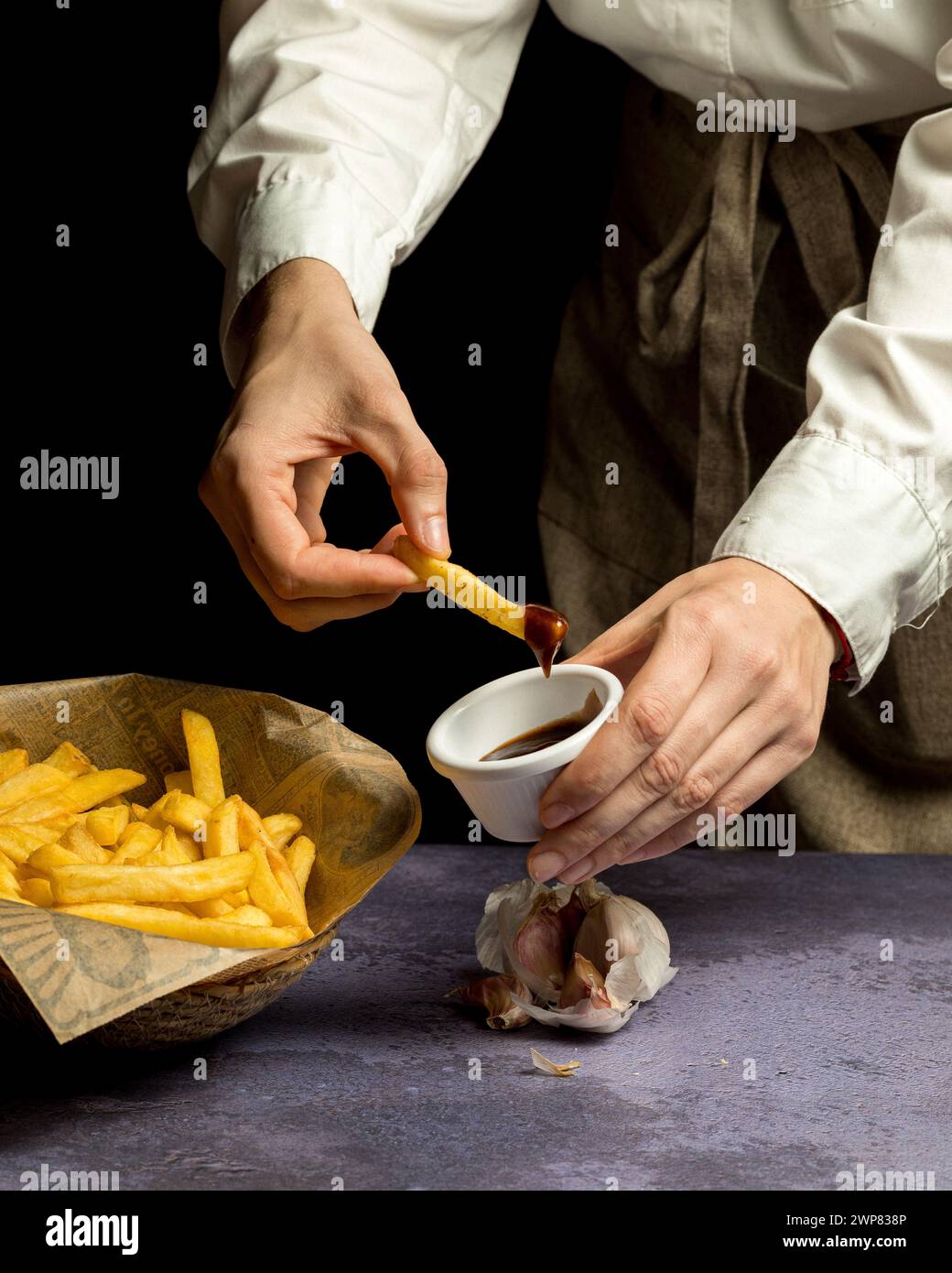 Mann, der mit Löffel Pommes isst, in eine Soße taucht Stockfoto