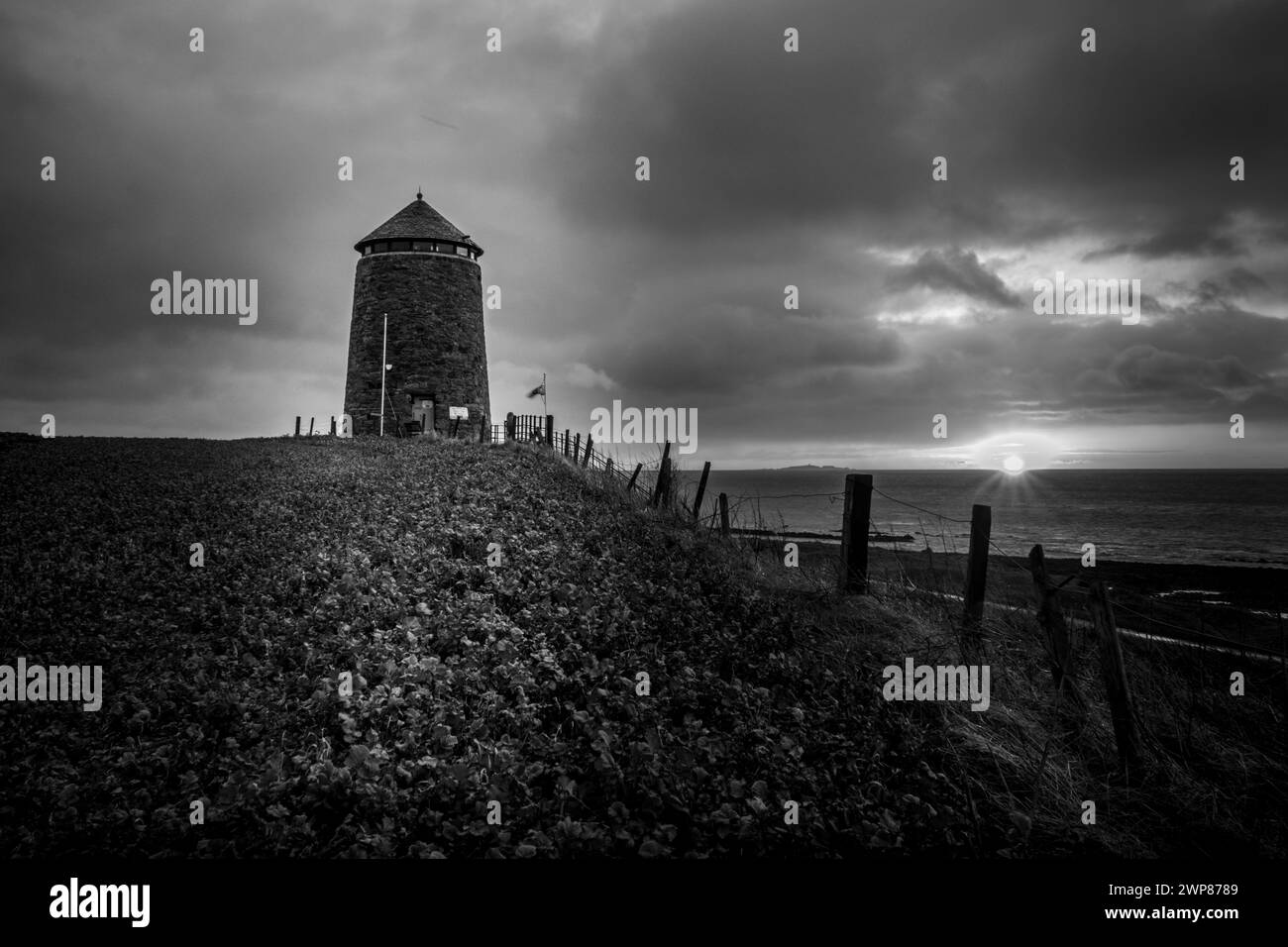 Ein kleines Leuchthaus auf einem Hügel am Meer Stockfoto