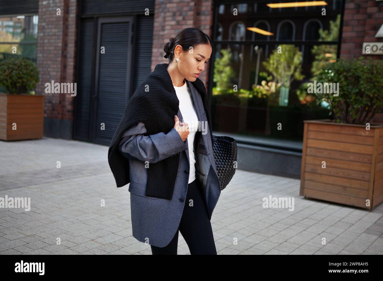 Stylische Modefrau schlendert die Straße in mehrlagiger Kleidung in einem Oversize-Blazer und schwarzen Leggings. Modisches Outfit, Street-Style. Stockfoto