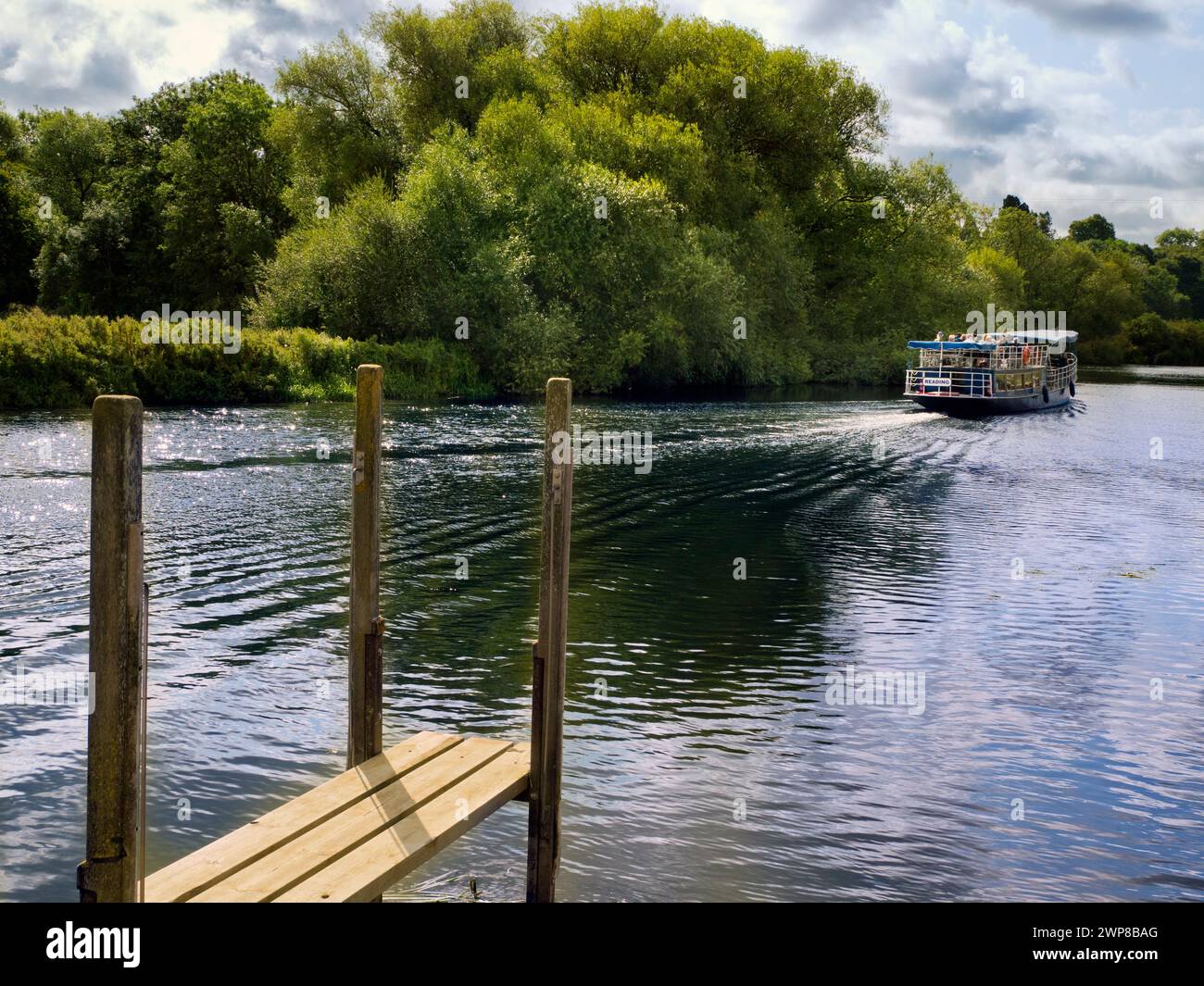 Mitten im Sommer bietet sich eine friedliche Landschaft auf der Themse, während ein Vergnügungsboot auf einem malerischen Flussabschnitt vorbeifährt. Das ist die Besichtigungstour, die Stockfoto