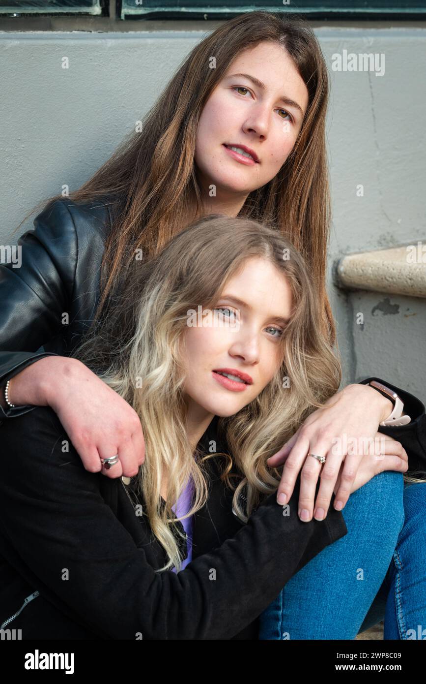Zwei Mädchen, eine Brünette und eine Blondine, sitzen auf der Stadtreppe Stockfoto