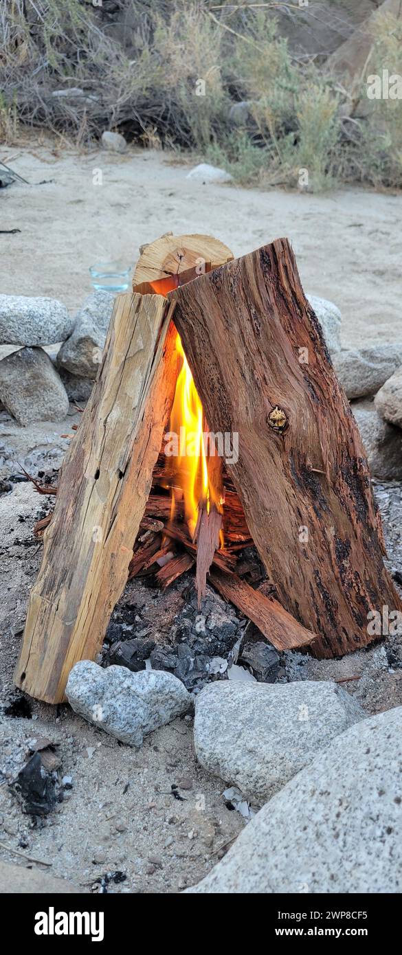 Ein von Felsen und Holz beleuchtetes Feuer am Strand Stockfoto