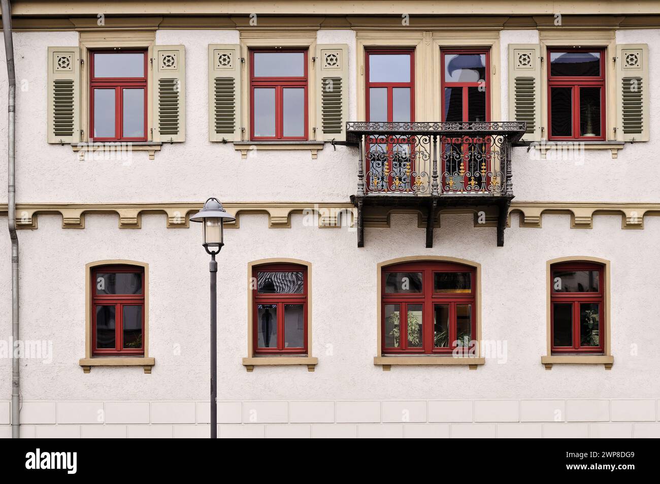 Eine Person mit Hund sitzt auf einem Balkon mit Blick auf die Stadt mit roten Fenstern Stockfoto