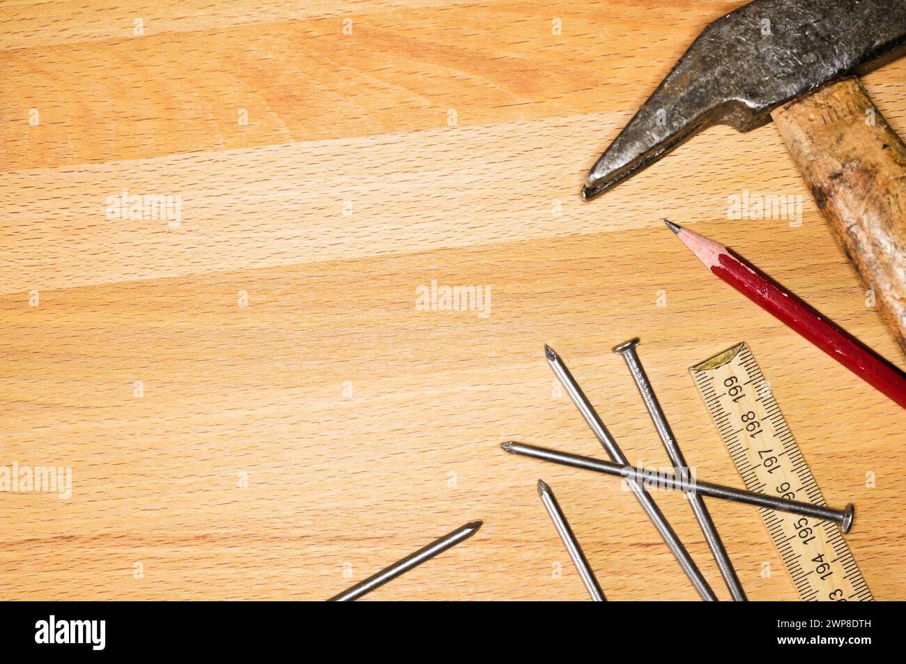 Ein Hammer, Nägel, Maßband und Bleistift auf einem Holzbrett Stockfoto