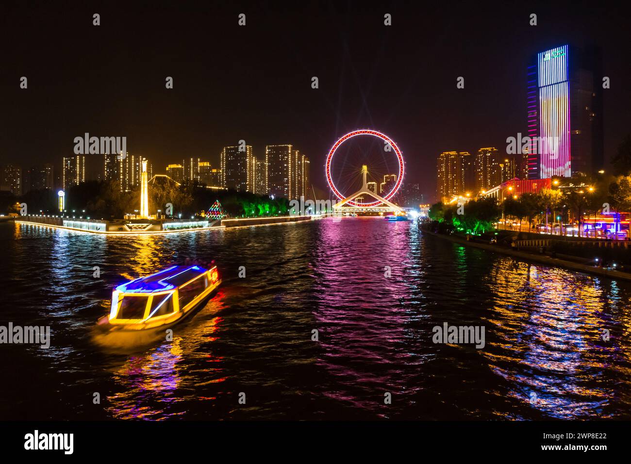 Nachtansicht über das beleuchtete Touristenboot und das Riesenrad in Tianjin, China Stockfoto