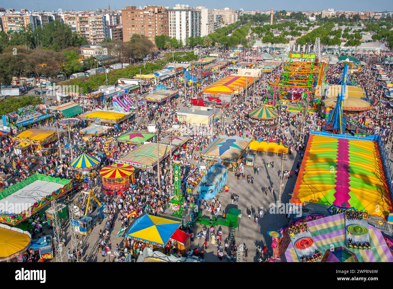 Die Menschenmassen genießen Fahrgeschäfte und Attraktionen auf der lebhaften Aprilmesse in Sevilla. Stockfoto